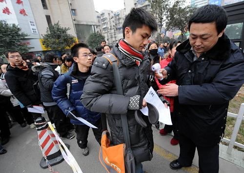 1月16日,南京廣播電視大學考點的工作人員在查驗考生準考證,并為考生測量體溫。新華社記者 孫參 攝