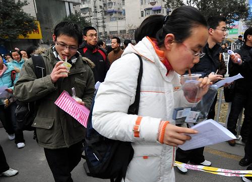 1月16日,在南京廣播電視大學考點,兩名考生一邊“補充能量”一邊趕著進場。新華社記者 孫參 攝