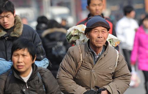2月3日,河南省蘭考縣71歲的農(nóng)民工齊伴人(右)背著行囊在鄭州火車站準(zhǔn)備乘火車回家過年。隨著春節(jié)的臨近,鄭州火車站迎來返鄉(xiāng)高峰,車站采取了一些相應(yīng)措施引導(dǎo)旅客進(jìn)出站,返鄉(xiāng)客流井然有序。新華社記者 趙鵬 攝