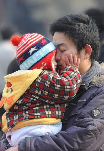 2月3日,一名懷抱小孩的男子在鄭州火車站廣場(chǎng)候車,準(zhǔn)備乘火車前往廣西過年。新華社記者 趙鵬 攝