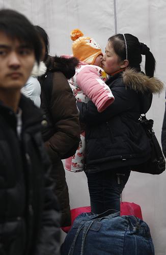 2月3日,在廣場(chǎng)上等候進(jìn)站的王愛(ài)蓮正用自己的吻為4個(gè)月大的孩子取暖。新華社記者 裴鑫 攝