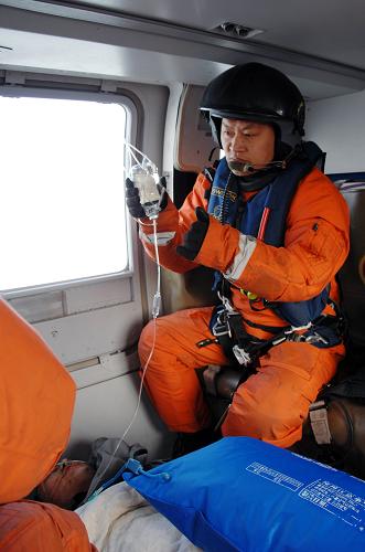 2月3日,交通運(yùn)輸部北海救助飛行隊(duì)隊(duì)員王軍在直升機(jī)上為傷者輸液。新華社發(fā)(馮小熒 攝)