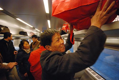 2月2日,在從杭州始發(fā)至南昌的動(dòng)車組D297次列車上,來(lái)自江西省鷹潭市的農(nóng)民工陳根生在放置行李。新華社發(fā)(黃宗治 攝)