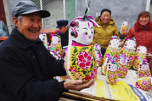3月17日,一位老人在山東濱州市惠民縣皂戶李鄉(xiāng)火把李村的“泥娃娃廟會”上選購泥娃娃。新華社發(fā)(董乃德 攝)