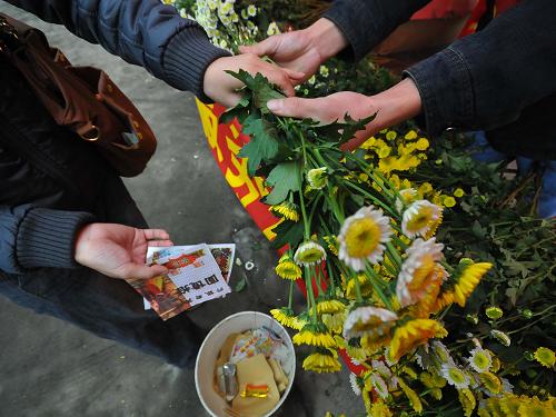 4月4日,在廣西梧州仙風(fēng)山墓園的“鮮花換紙錢(qián)”免費(fèi)兌換處,一名前來(lái)掃墓的市民將紙錢(qián)換成鮮花。新華社發(fā)(何鎏 攝)