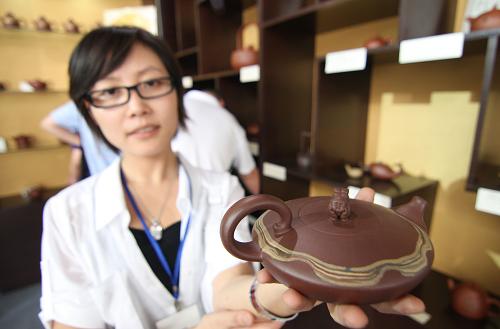 6月4日,一位工作人員展示工藝美術(shù)大師呂俊杰設(shè)計(jì)的紫砂壺作品。新華社發(fā)(梁志杰 攝)