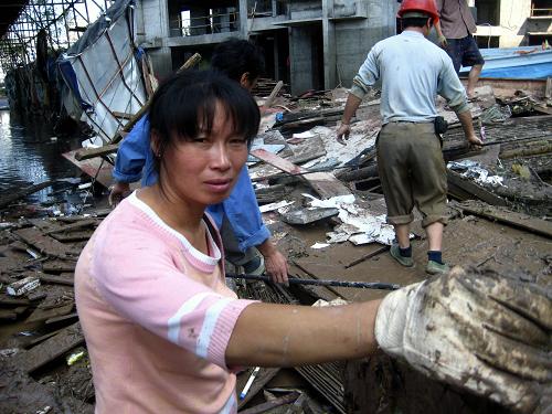 7月20日,工人在被洪峰沖毀的國(guó)道318線渠江二橋工地清理。新華社發(fā) (鄧良奎 攝)