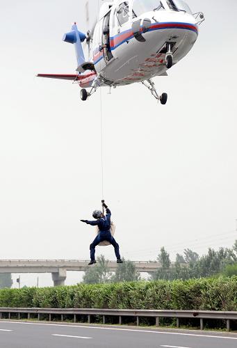 7月22日,交通運輸部北海救助飛行隊S-76直升機趕到模擬事故現(xiàn)場懸停,救援人員攜帶工具降落地面。當日,“遼寧-2010”高速公路直升機救援演習(xí)在沈陽至大連高速公路舉行。這是中國首次在高速公路動用直升飛機對突發(fā)重特大事故進行救援演習(xí),交通運輸部救助打撈局、遼寧省政府應(yīng)急辦等20個單位參演。新華社記者 徐揚 攝