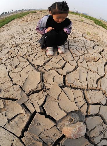 一名兒童好奇地觀察洞庭湖因枯水而裸露的湖床(11月14日攝)。新華社記者 龍弘濤 攝