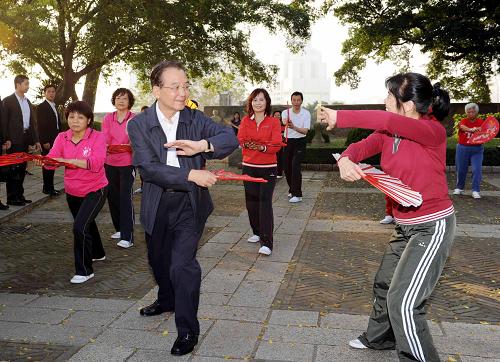 11月14日,國務(wù)院總理溫家寶來到澳門大炮臺(tái)花園,同在這里晨練的市民親切交流,一起練習(xí)太極拳并學(xué)練太極扇。新華社記者 饒愛民 攝