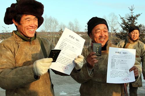 11月29日,黑龍江省黑河市新生鄉(xiāng)鄂倫春族獵民展示剛剛領(lǐng)到的狩獵證和持槍證。新華社發(fā)(呂濤 攝)