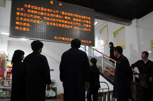 11月30日,葉青兜農(nóng)貿(mào)市場經(jīng)營戶在觀看減免“微利菜”經(jīng)營戶攤位費的通知。新華社記者 韓傳號 攝