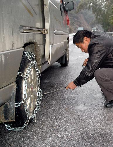 1月5日,司機(jī)給車輪安裝防滑鏈。新華社記者 何程 攝