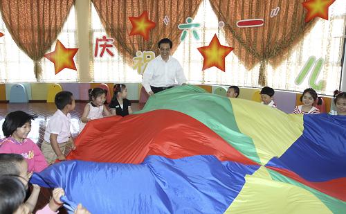 這是胡錦濤同小朋友一起掀動(dòng)彩色綢布做“彩虹傘”游戲。新華社發(fā)