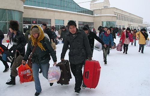 12月31日,在威?;疖囌菊九_,旅客冒雪乘車。新華社發(fā)(于啟波 攝)