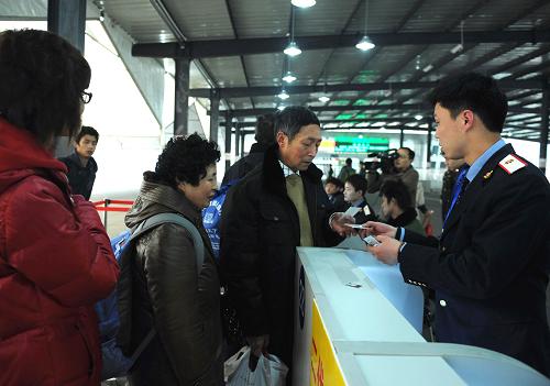 2月14日,重慶火車北站一位工作人員正在為K690次車旅客檢票。當(dāng)日是重慶試行火車票實(shí)名制檢票乘車的第一天。重慶火車站、火車北站為了讓旅客順利、快速通過(guò)檢票,專設(shè)了112個(gè)驗(yàn)證口,兩站職工滿員上崗服務(wù)春運(yùn)。新華社記者 周衡義攝