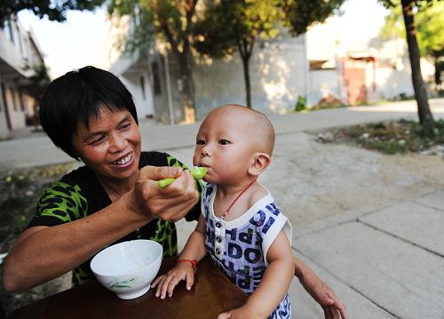 移民向興華(左)在家門口給孫子喂晚餐(8月4日攝)。新華社記者 李健 攝