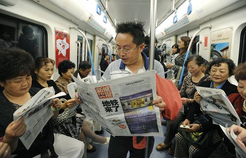 9月27日,乘坐首趟試運營地鐵列車的市民在車廂里看報紙。新華社記者 江宏景攝