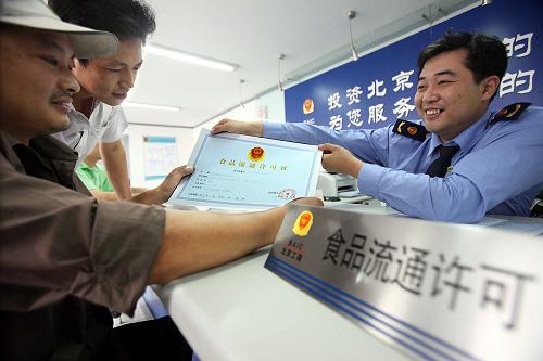 9月17日,個體工商戶余明(左)從北京市工商局西城分局新街口工商所工作人員手中領(lǐng)到食品流通許可證。當日,北京市西城區(qū)首批個體工商戶領(lǐng)到了食品流通許可證。根據(jù)國家工商總局《食品流通許可證管理辦法》,從9月1日起,北京市工商局正式啟動食品流通許可工作,對全市范圍內(nèi)的商場、超市、市場、食雜店以及影劇院、加油站、報刊亭等從事批發(fā)或零售預(yù)包裝食品、散裝食品的經(jīng)營企業(yè)和個人實施食品流通許可。為做好許可證的受理、發(fā)放工作,北京市各級工商部門均在服務(wù)大廳設(shè)立了專門窗口,為申請人提供高效、便捷、優(yōu)質(zhì)的服務(wù)。新華社記者 張旭 攝