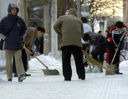 1月4日,一家單位的員工在清理人行道上的積雪。新華社記者 公磊 攝