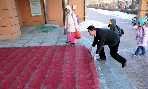 1月5日,天津市模范小學(xué)的老師在教學(xué)樓門前鋪設(shè)地毯保學(xué)生安全進(jìn)入學(xué)校。 新華社記者 劉海峰 攝