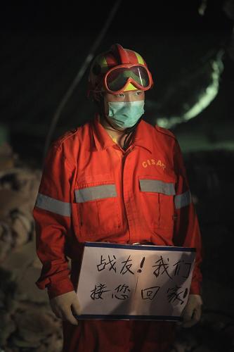 1月16日,在海地太子港,一名中國(guó)國(guó)際救援隊(duì)隊(duì)員在聯(lián)合國(guó)駐海地穩(wěn)定特派團(tuán)倒塌大樓現(xiàn)場(chǎng)手持“戰(zhàn)友!我們接您回家!”的標(biāo)語(yǔ)。當(dāng)日,中國(guó)國(guó)際救援隊(duì)在海地太子港地震現(xiàn)場(chǎng)挖掘出一具中方失蹤人員遺體,并舉行了簡(jiǎn)短的現(xiàn)場(chǎng)默哀儀式。新華社記者 邢廣利 攝