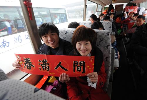 2月5日,河南信陽籍農(nóng)民工在鄭州人民會堂免費乘車回家,兩名青年在展示團委贈送的春聯(lián)。當日,河南省信陽籍在鄭州務(wù)工青年免費集中乘車儀式在鄭州舉行。共青團信陽市委和信陽駐鄭團工委組織了這次主題為“咱們一起回家過年”的活動,140名在鄭州務(wù)工青年乘4輛大巴集中返鄉(xiāng)。新華社記者 趙鵬 攝
