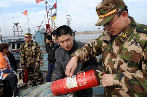 青島營海公安邊防派出所警官趙長城(右一)在檢查漁船上滅火器的出廠時(shí)間(3月29日攝)。新華社記者 李紫恒 攝