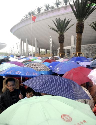 4月26日,在上海世博園浦東園區(qū),參觀者在雨中打傘排隊(duì)等待參觀沙特阿拉伯館。當(dāng)日,上海世博園舉行第六場試運(yùn)行,不少參觀者在雨中游覽上海世博園。新華社記者 吳曉凌 攝
