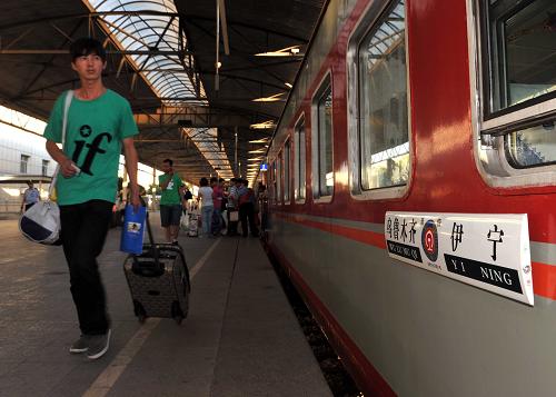7月1日,旅客提著行李在烏魯木齊火車站準(zhǔn)備登上通往伊犁的列車。 新華社記者 江文耀 攝