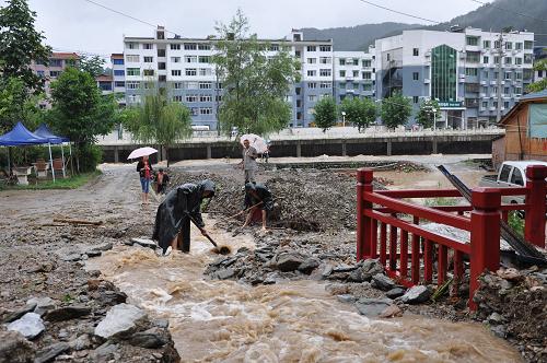 8月19日,青川縣城對(duì)岸東山居民小區(qū)群眾在疏通排水溝,積極自救。新華社發(fā)(王生偉 攝)