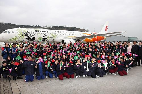 12月18日,迎接“開開”“心心”的澳門小學(xué)生與各界嘉賓在澳門國(guó)際機(jī)場(chǎng)大熊貓專機(jī)前合影。新華社記者 張金加 攝
