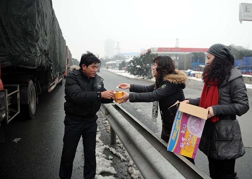 1月21日,九江市潯陽區(qū)白水湖街道工作人員為滯留司機(jī)送上方便面。新華社記者 周科 攝
