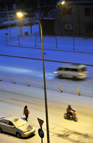 2月10日清晨,行人和車輛在北京街頭冒雪前行。新華社記者 馬寧 攝