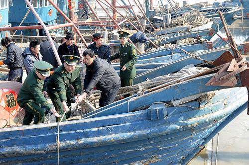 2月21日,青島營海邊防派出所警官在漁港碼頭對即將出海的漁船進(jìn)行海冰防范安全檢查。新華社記者 李紫恒 攝