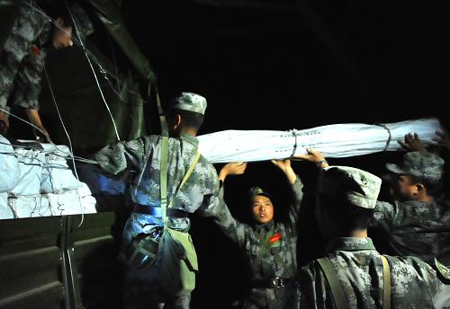 3月14日凌晨,解放軍戰(zhàn)士在重災(zāi)區(qū)弄璋鎮(zhèn)賀哈村搬運(yùn)帳篷。新華社記者 陳海寧 攝