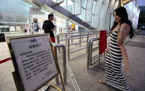 5月17日,一顧客在海南省三亞市免稅店入口處觀看提示牌。新華社發(fā)(陳文武 攝)