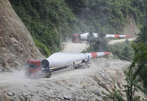在廣西資源縣境內的山區(qū)公路上,載重汽車拉著風力發(fā)電機組葉片前往金紫山風電場(7月5日攝)。新華社發(fā)(張克祥 攝)