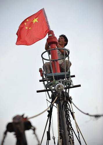 7月31日,海南瓊海潭門港的漁民在桅桿上懸掛國(guó)旗。新華社記者 郭程 攝
