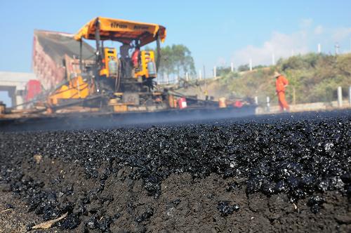 10月22日,在廣西欽崇高速公路上思縣路段,工人在鋪設瀝青路面。新華社發(fā)(梁富盈 攝)