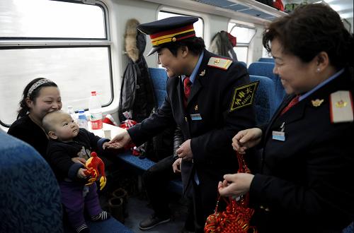北京鐵路局張家口車務(wù)段列車長牛桂芳(中)在L1955次列車上將龍年吉祥物送給旅客(2012年1月14日攝)。北京鐵路局自1月8日春運(yùn)啟動后,抽調(diào)7100多名有乘務(wù)經(jīng)驗(yàn)的工作人員值乘在521對臨時客運(yùn)列車上。他們放棄節(jié)日休息,默默奉獻(xiàn),盡最大努力為旅客服務(wù)。新華社發(fā)(朱河 攝)