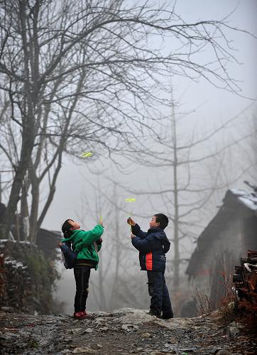 1月9日,在廣西全州縣蕉江瑤族鄉(xiāng)大源村,9歲的阮紅婷(左)和伙伴在回家的路上玩玩具。新華社記者 黃孝邦 攝