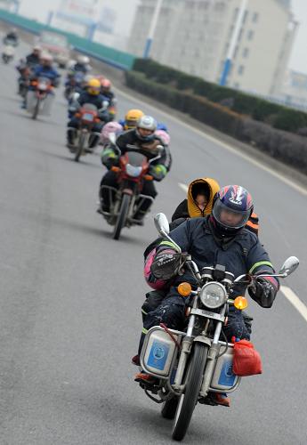 1月17日,回鄉(xiāng)過年的江西籍務工人員騎摩托車經(jīng)過浙江衢州市境內(nèi)。新華社記者 韓傳號 攝