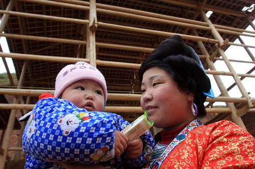 1月6日,在廣西融水縣大年鄉(xiāng)林姑新村,一名苗家女抱著孩子在吊腳木樓前玩耍。春節(jié)臨近,作為易地扶貧搬遷項目之一,廣西融水縣大年鄉(xiāng)林姑新村正加緊建設施工,力爭趕在春節(jié)前全部完工。據(jù)了解,融水縣去年共投入3000多萬元實施地質(zhì)災害村屯和生存條件惡劣村屯易地搬遷、茅草房改造等項目,改善了近4000戶農(nóng)戶住房困難的狀況。新華社發(fā)(龍濤 攝)