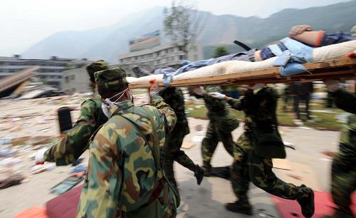 2008年5月16日,官兵們抬著營救出來的幸存者在城區(qū)內飛奔。 新華社發(fā)