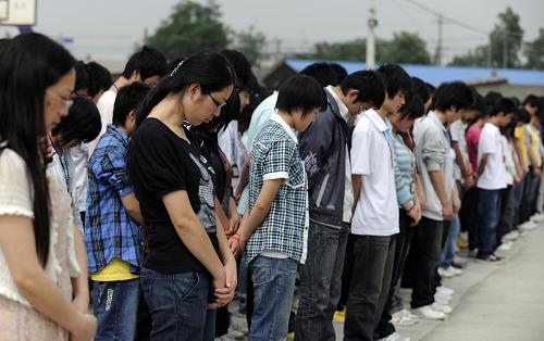 2009年5月11日,在德陽市東汽中學的臨時板房教學點,師生們在升旗儀式默哀,紀念在大地震中遇難的師生。 新華社發(fā)