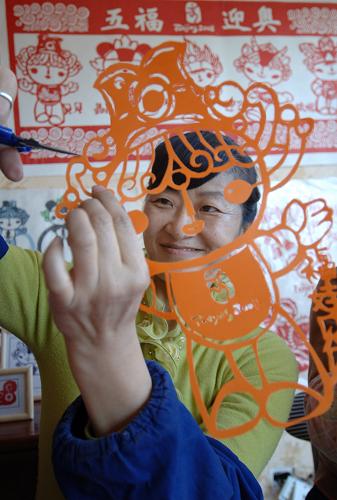 2008年3月26日,新疆維吾爾自治區(qū)文聯(lián)民間剪紙藝術(shù)協(xié)會(huì)的工作人員在剪福娃,看著自己手中剪出的栩栩如生的福娃,臉上樂開了花。新華社發(fā)(楊萬江攝)