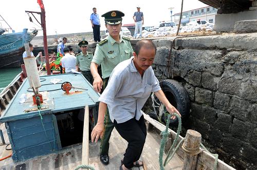 7月9日,王哥莊邊防派出所警官劉佳偉在仰口碼頭查處一艘涉嫌出海偷漁的漁船。新華社記者 李紫恒 攝
