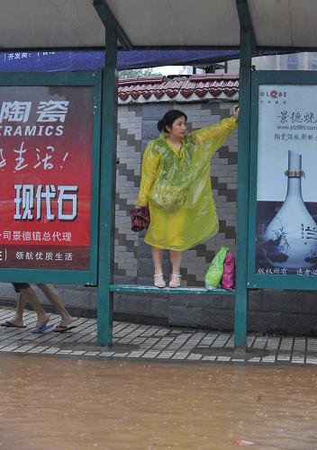 7月15日,景德鎮(zhèn)市中心積水,一位市民在等待公交車。新華社記者 章武 攝