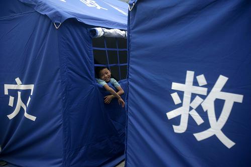 8月10日,在甘肅省舟曲縣第三中學受災(zāi)群眾安置點,一名小男孩趴在帳篷窗口。新華社發(fā)(王翮 攝)
